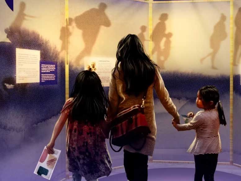 Image of a woman with two children, looking at a museum exhibit, photographed from behind