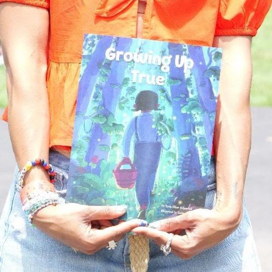Hands holding a copy of "Growing Up True"